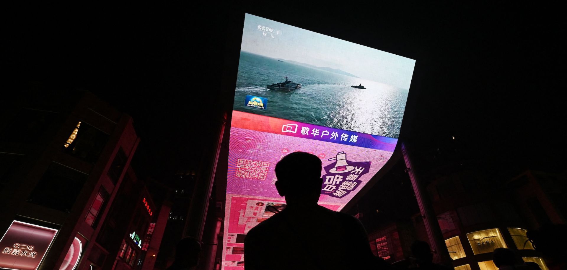 A man watches a news program about Chinese military drills surrounding Taiwan on a giant screen outside a shopping mall in Beijing on Oct. 14, 2024.