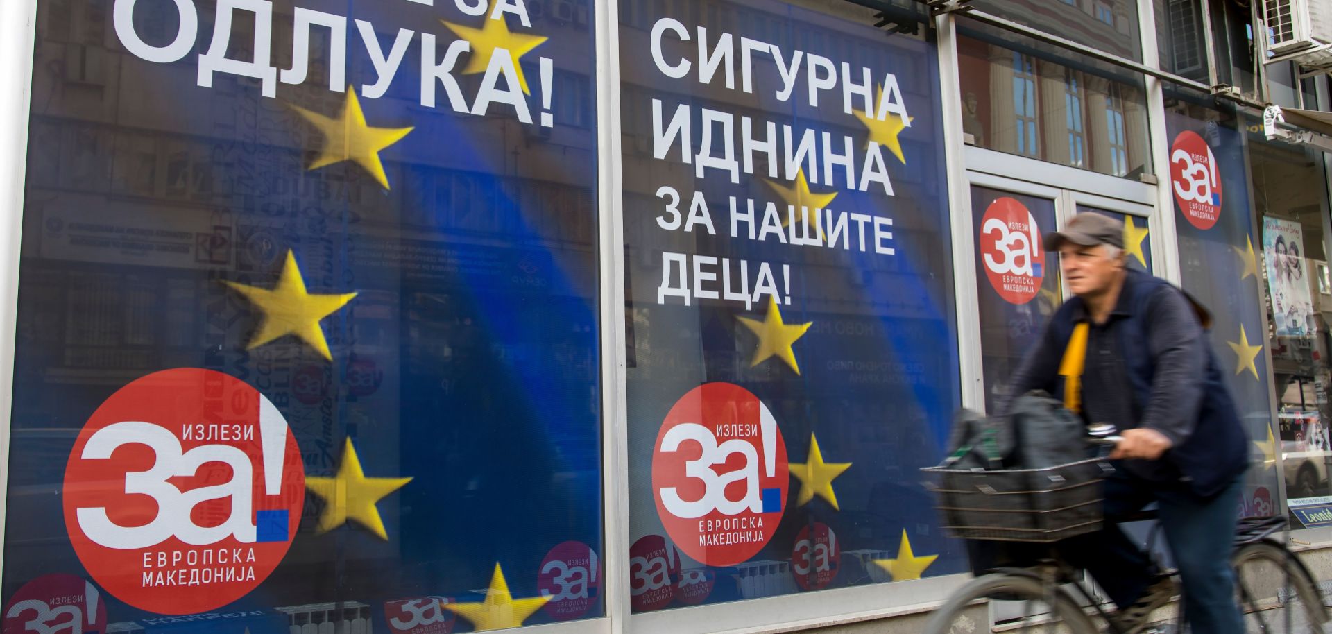 A man rides his bicycle past campaign posters reading 'For a European Macedonia' in Skopje on Sept. 29, 2018. Macedonia is holding a referendum on Sept. 30 on whether to change the country's name.