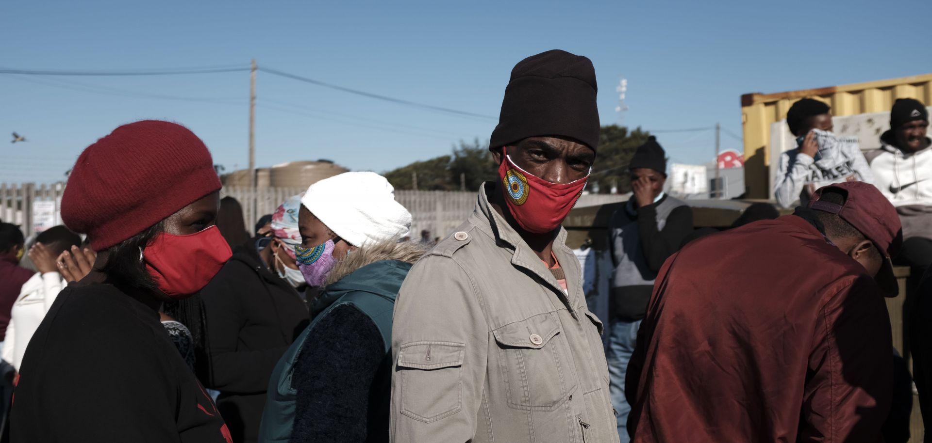 People stand in line to receive grant payments from the South African Social Security Agency (SASSA) in Khayelitsha, a township located near Cape Town, on May 4, 2020.
