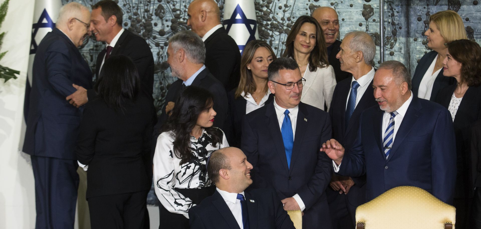 Israeli Prime Minster Naftali Bennett (bottom center) talks with members of his new coalition government before posing for a group photo at the President's Residence in Jerusalem on June 14, 2021. 