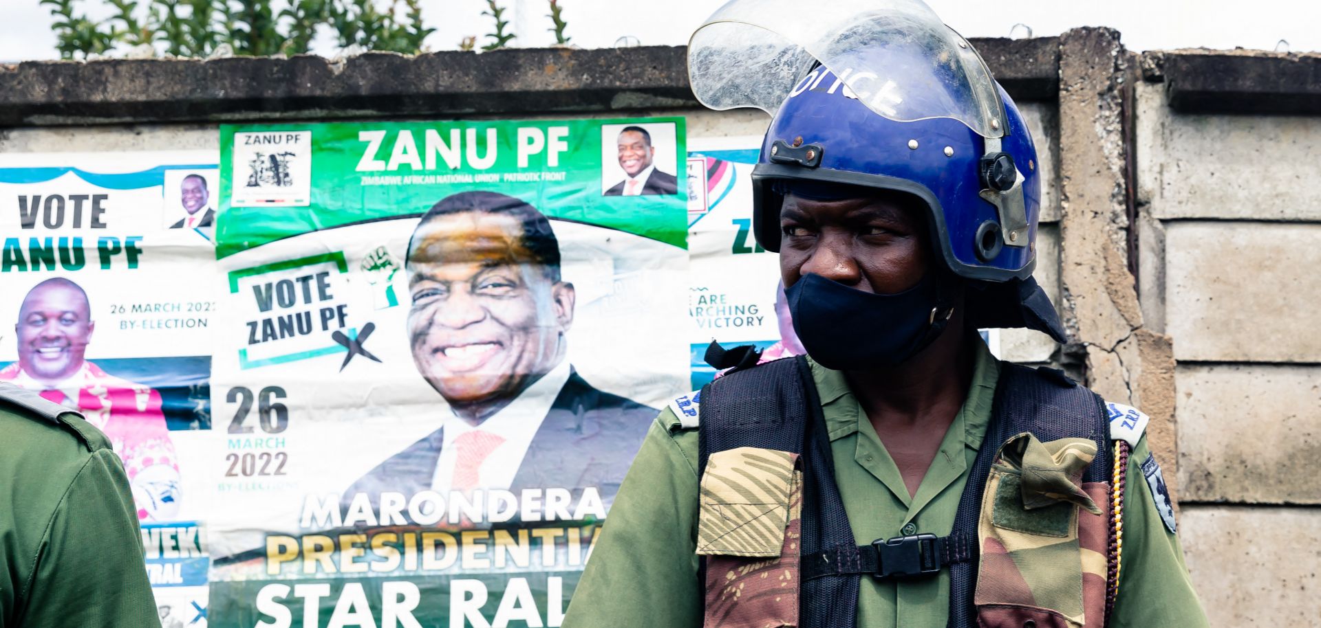 A police officer stands in front of an election poster for Zimbabwean President Emmerson Mnangagwa as he patrols outside a stadium where opposition leader Nelson Chamisa was holding a campaign rally in Marondera, Zimbabwe, on March 12, 2022. 