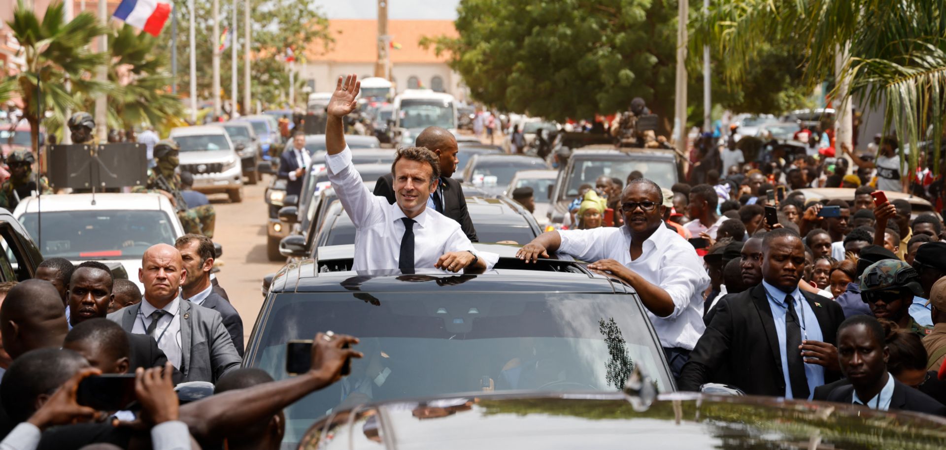 During the final day of the African tour that also included visits to Cameroon and Benin, French President Emmanuel Macron (left) waves to a crowd through the roof of a car in Bissau with Guinea-Bissau's President Umaro Sissoco Embalo. 