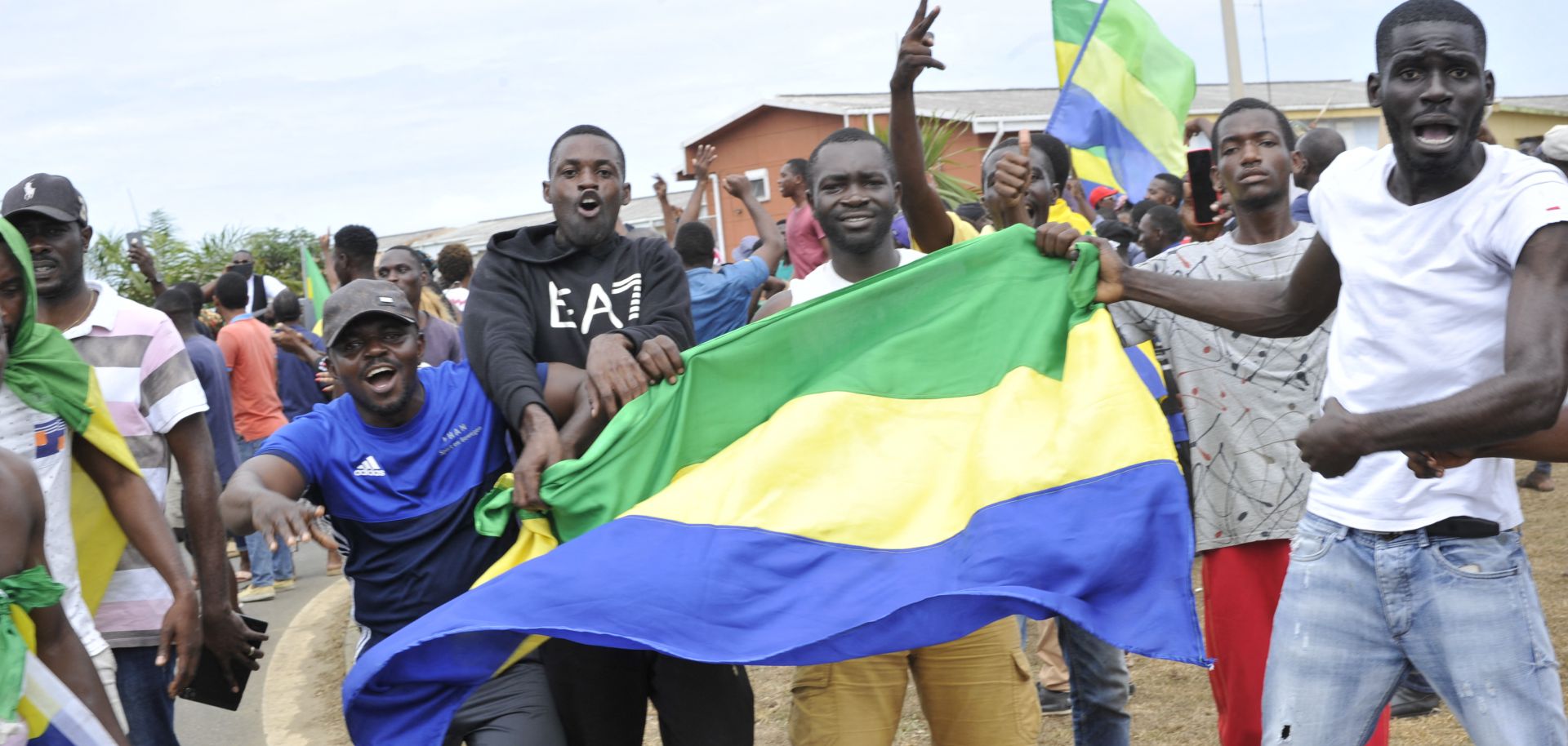 People hold up Gabon's national flag in the country's capital of Libreville on Aug. 30, 2023, as they celebrate after a group of military officers announced they were ''putting an end to the current regime'' and scrapping official election results that had handed another term to President Ali Bongo Ondimba. 