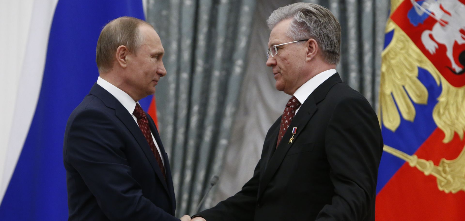 Russian President Vladimir Putin (left) shakes hands with Vladimir Bogdanov, CEO of Surgutneftegas oil and gas company, in Moscow on April 30, 2016.