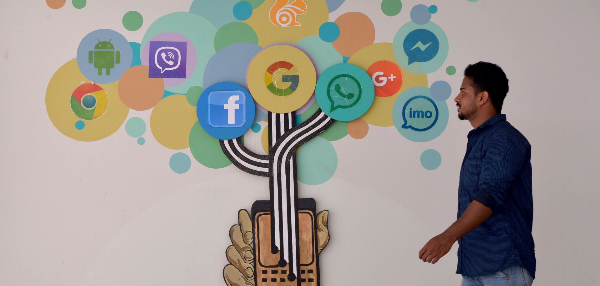 An Indian visitor walks past a mural of social media logos in Bangalore.