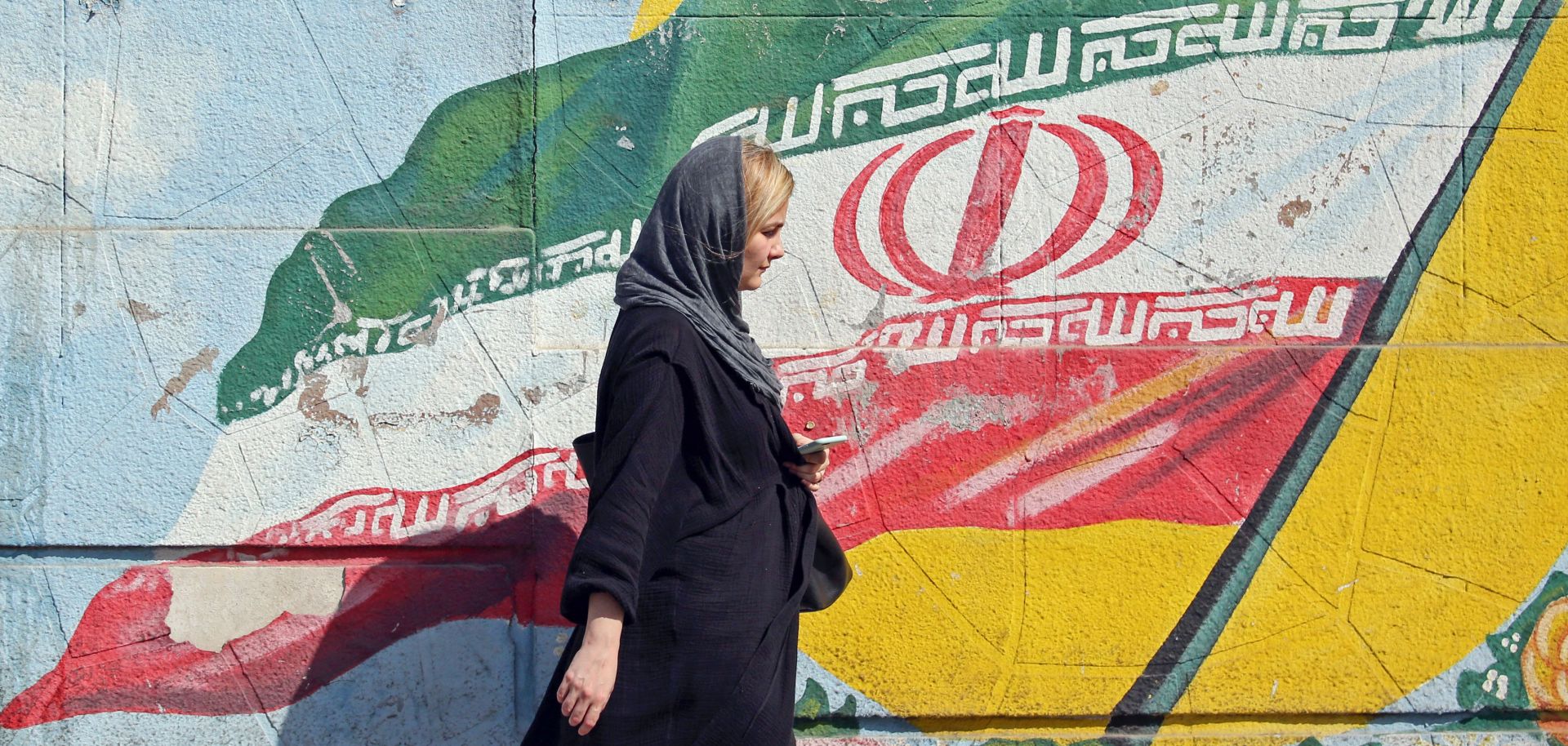 A pedestrian walks past a mural depicting the Iranian national flag in Tehran, Iran. 