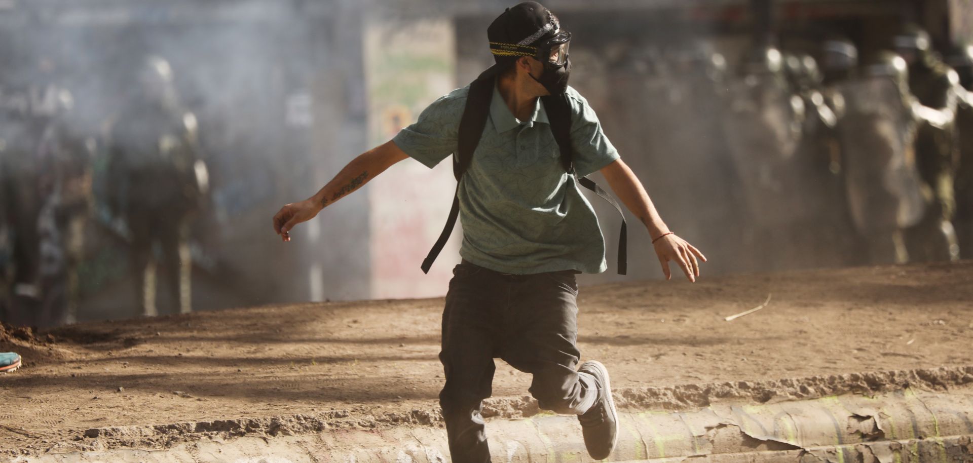 A man wearing a gas mask runs from a clash with police in Santiago, Chile, during a protest on Dec. 10, 2019.