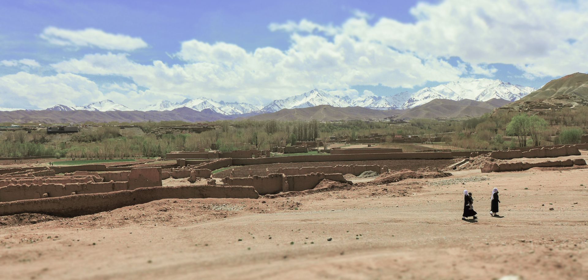 Villagers walk across a striking Afghan rural landscape.