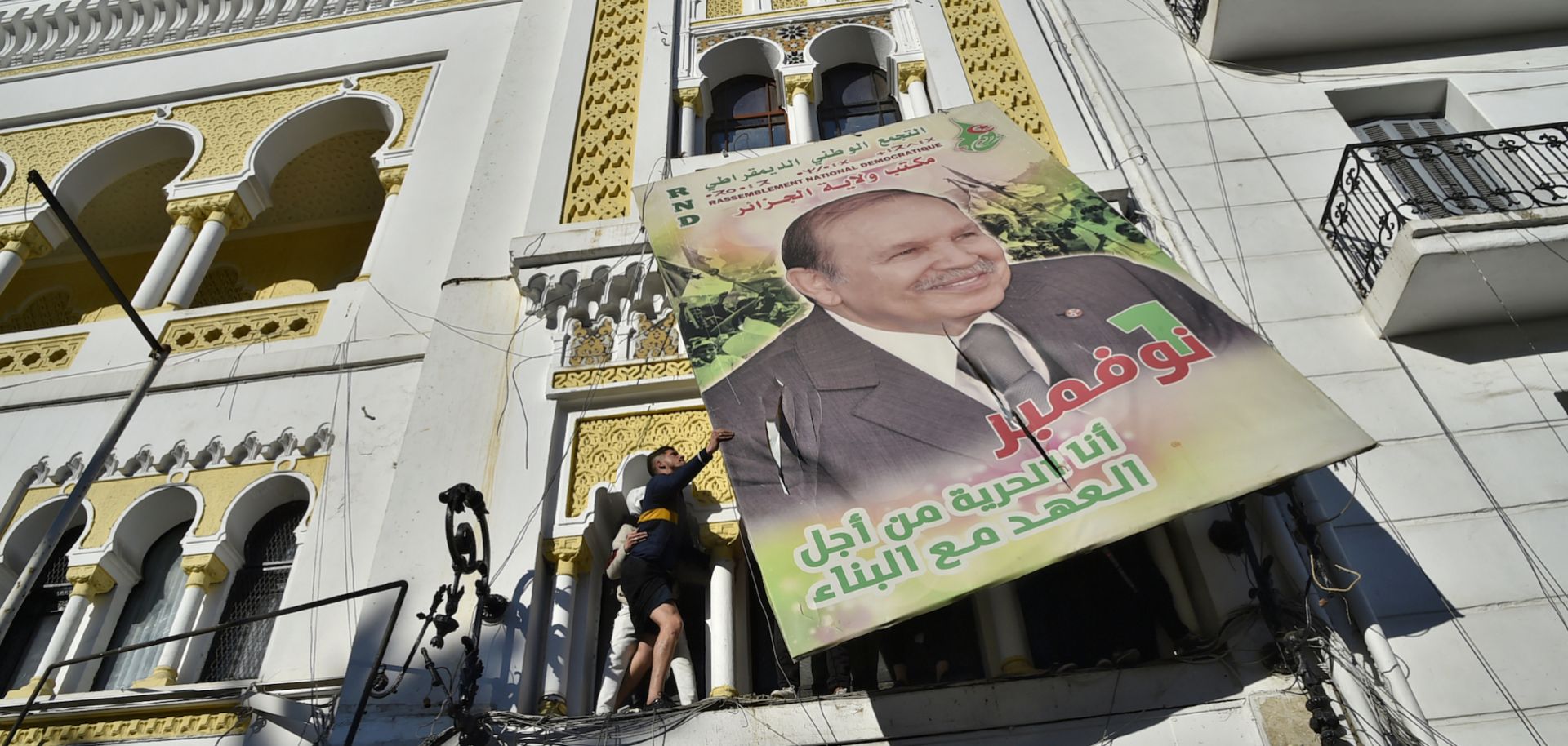 A billboard of Algerian President Abdel Aziz Bouteflika gets taken down in protest of fifth run for the presidency.