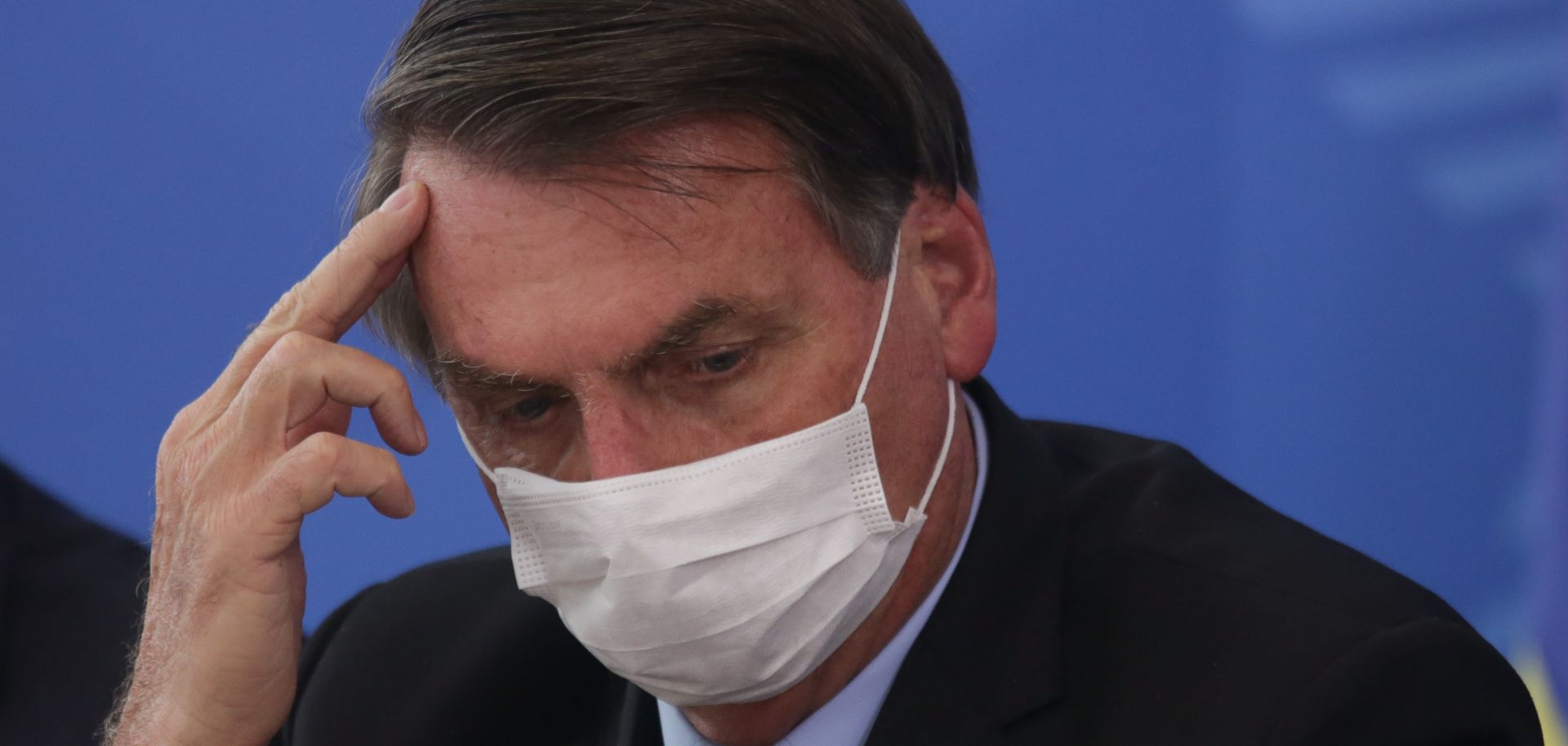Wearing a protective mask, Brazilian President Jair Bolsonaro takes to questions regarding the country's coronavirus outbreak during a press conference at the Planalto Palace in Brasilia on March 18, 2020.