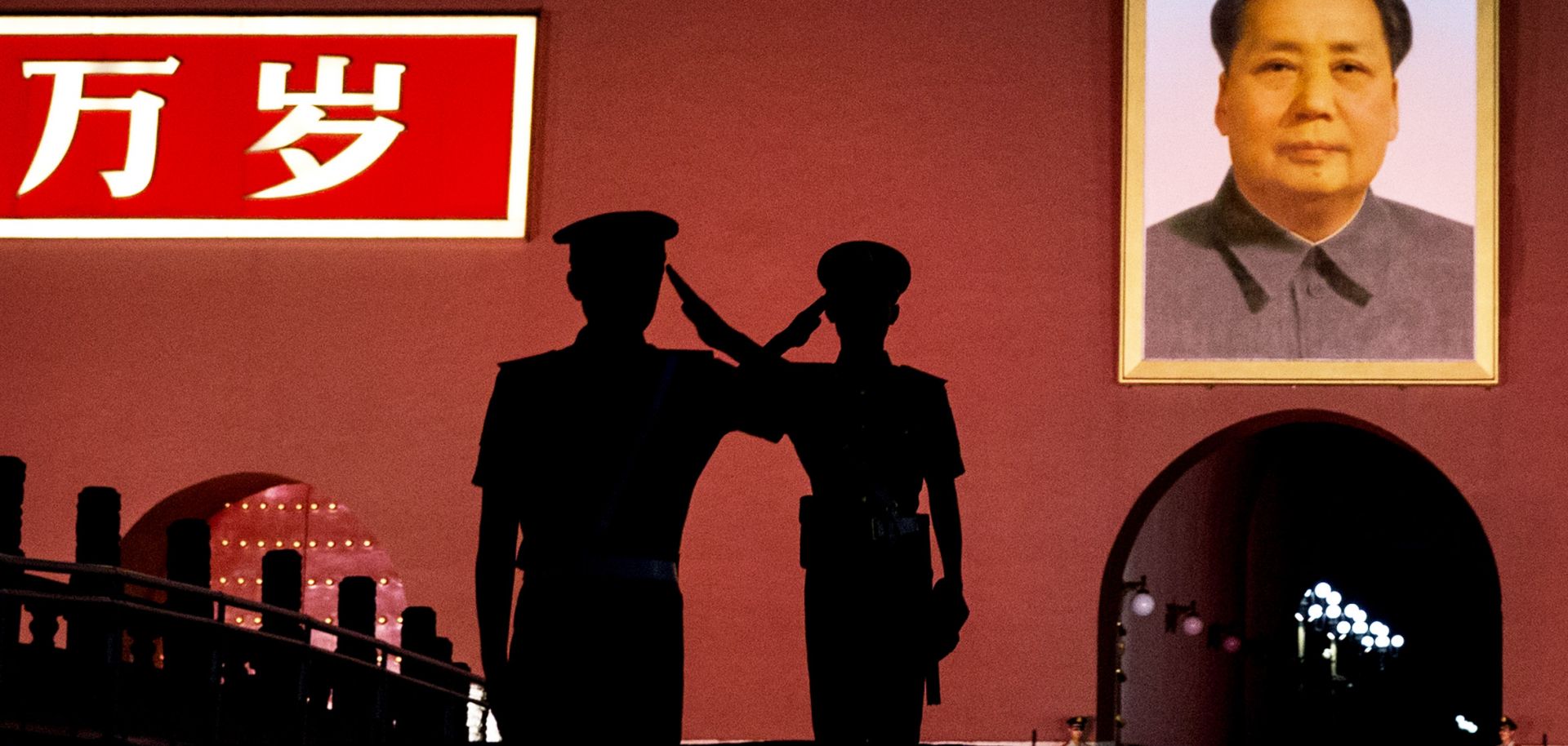 Chinese Paramilitary police officers salut each other as they stand guard below a portrait of the late leader Mao Zedong.