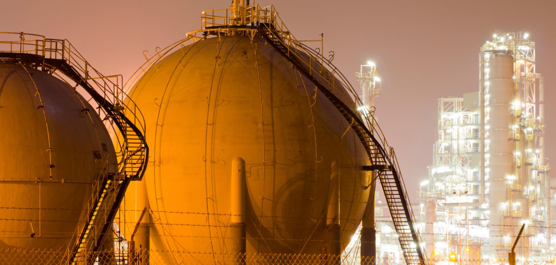 Storage tanks for liquefied natural gas sit in a large oil-refinery plant