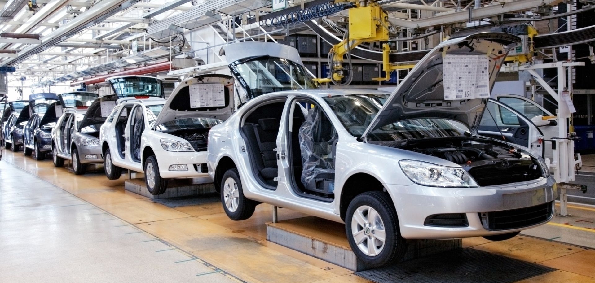 Cars sit on an assembly line.