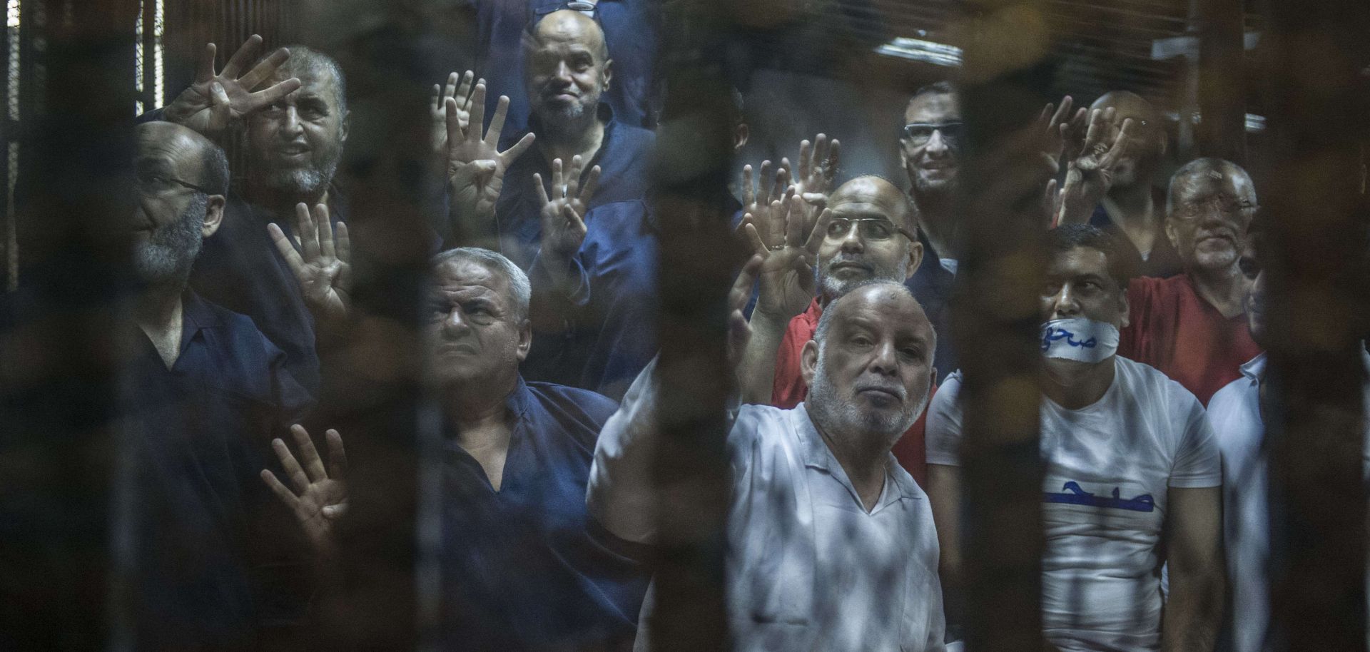 Egyptian Muslim Brotherhood senior members, including Khairat al-Shater (top left), gesture from the defendants' cage at the Egyptian Police Academy on the outskirts of Cairo on June 2, 2015.
