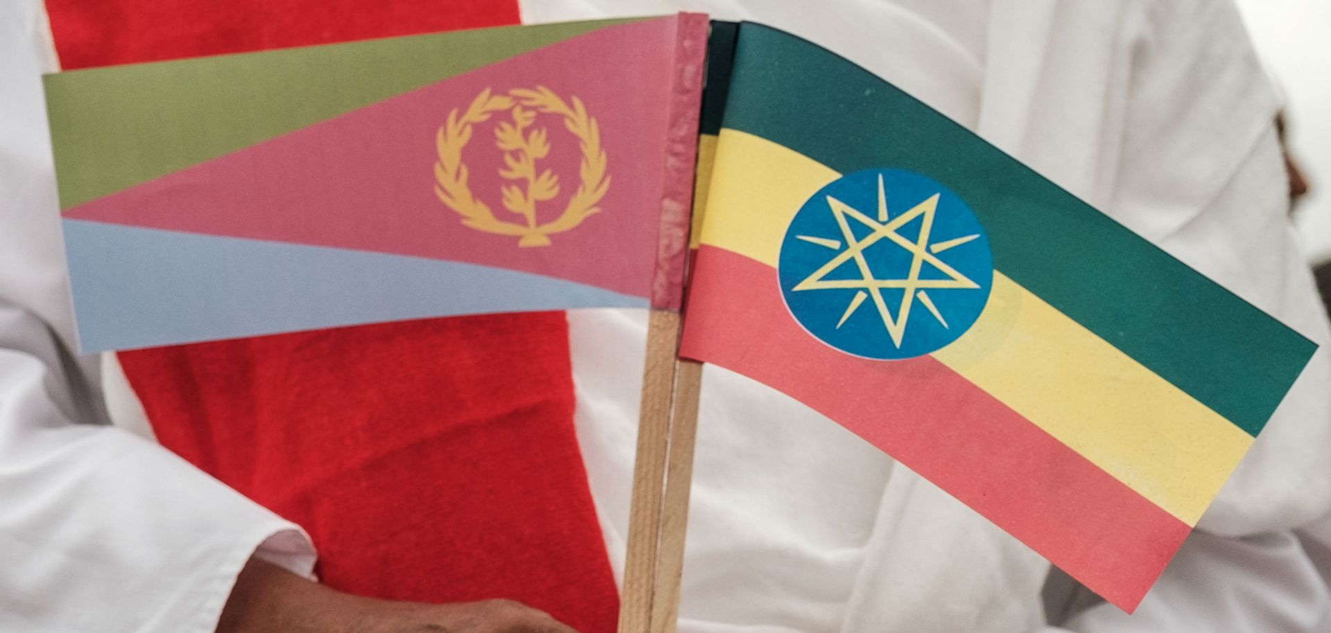 A man holds the flags of Eritrea, left, and Ethiopia as he waits for the arrival of Eritrea's president at an airport in Gondar, northern Ethiopia, on Nov. 9, 2018.