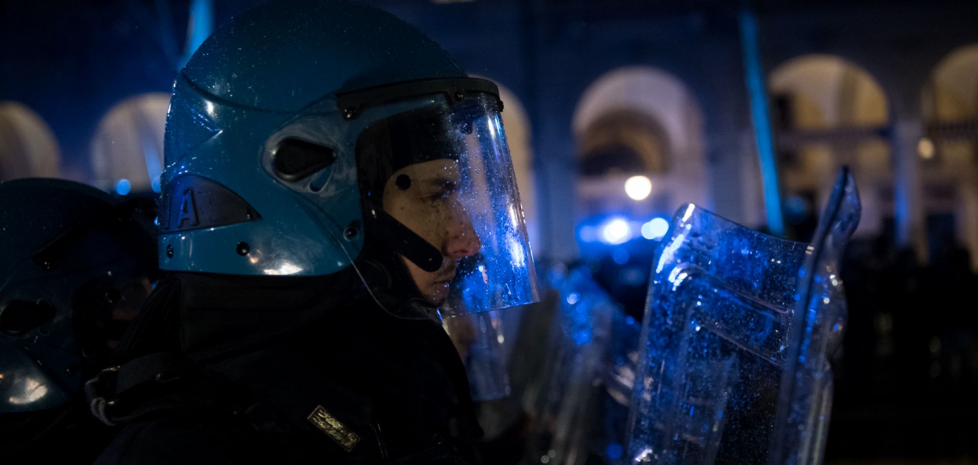 An Italian police officer in riot gear watches an anti-fascist counterdemonstration against a far-right meeting.
