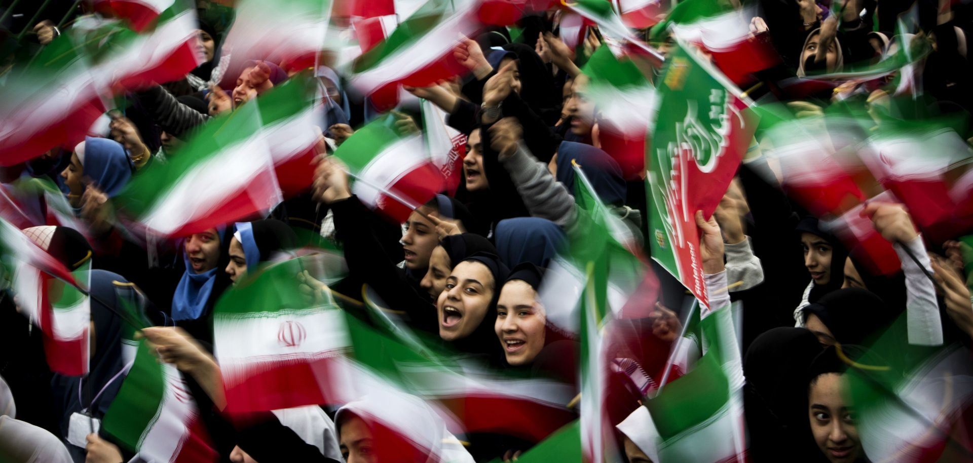 Iranian schoolgirls wave their country's flag at a rally on the anniversary of Iran's Islamic revolution. 