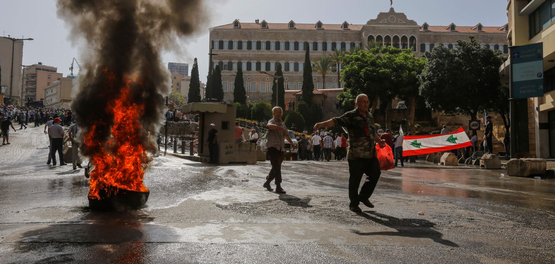 A protester passes a burning tire during a demonstration over feared pension cuts May 20, 2019, near the government's headquarters in Beirut.