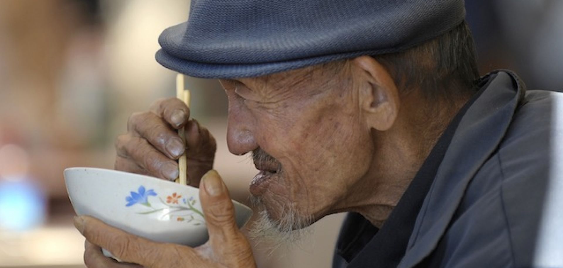 An elderly man tucks into some noodles on the street in Beijing.