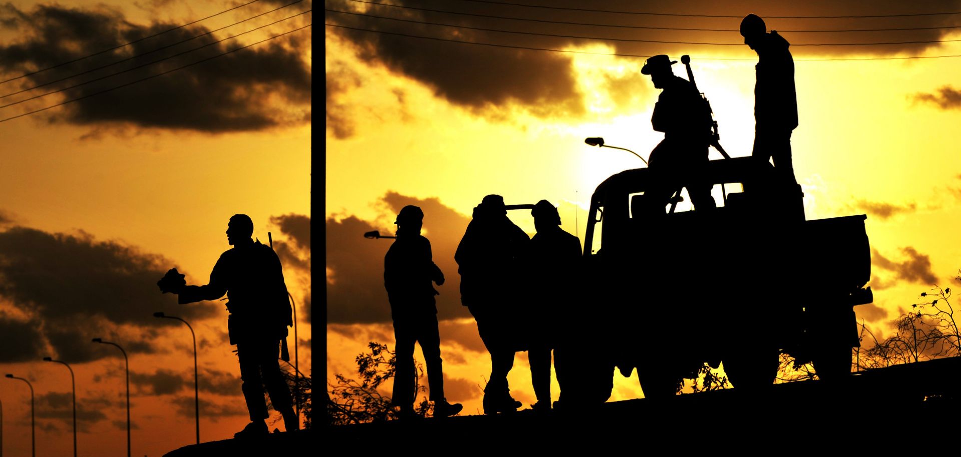Libyan rebels are silhouetted at sunset on March 7, 2011. Three years later, an Islamist coalition would mount another revolt meant to topple the country's newly elected government.