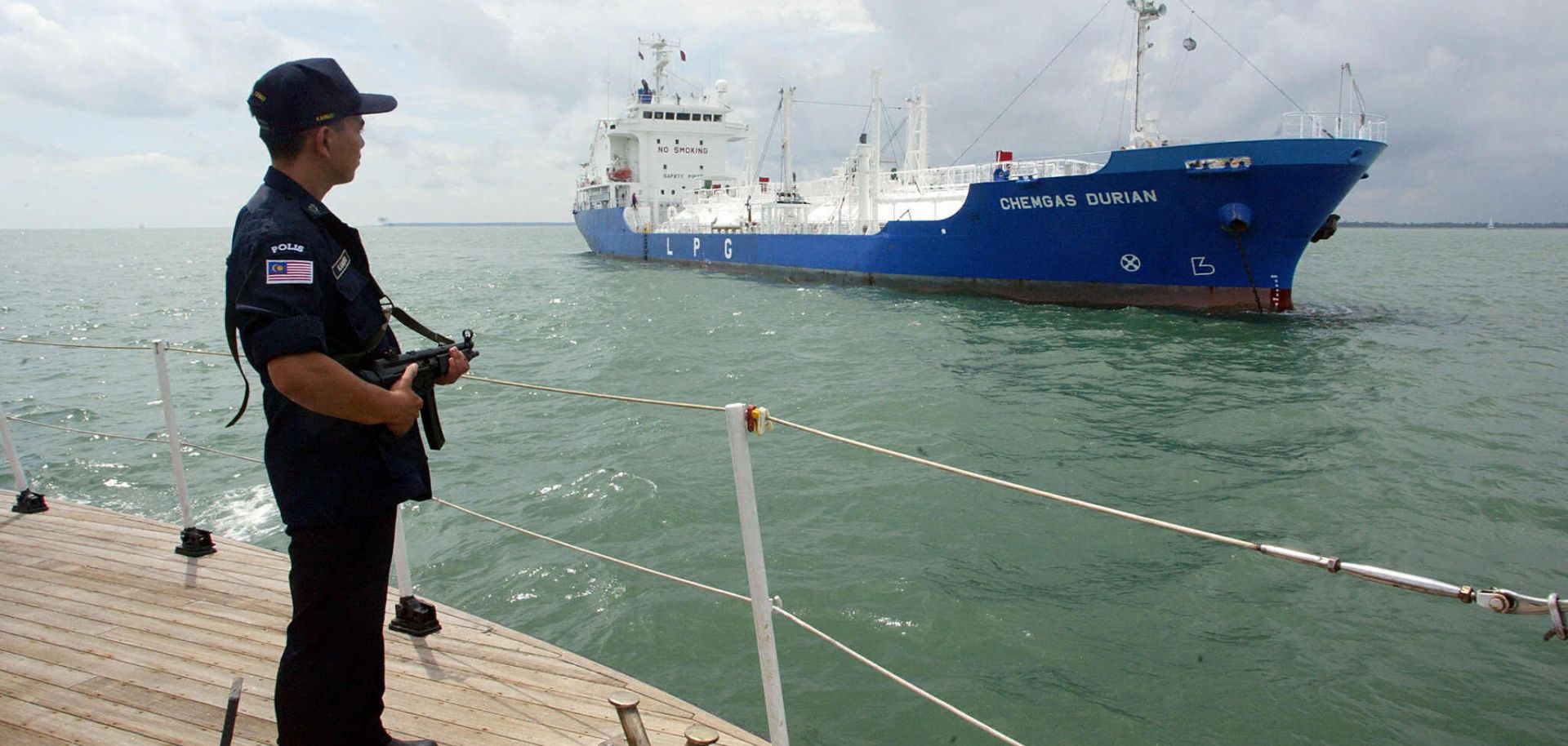 An armed marine policeman stands guard on the deck of his patrol boat.