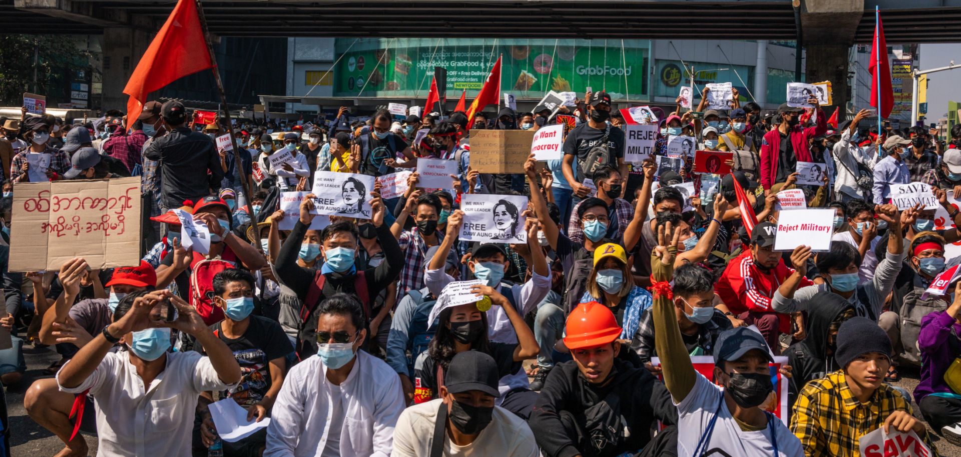 Anti-coup protesters wave red National League For Democracy (NLD) flags and raise three-finger salutes on Feb. 9, 2021, in Yangon, Myanmar. 