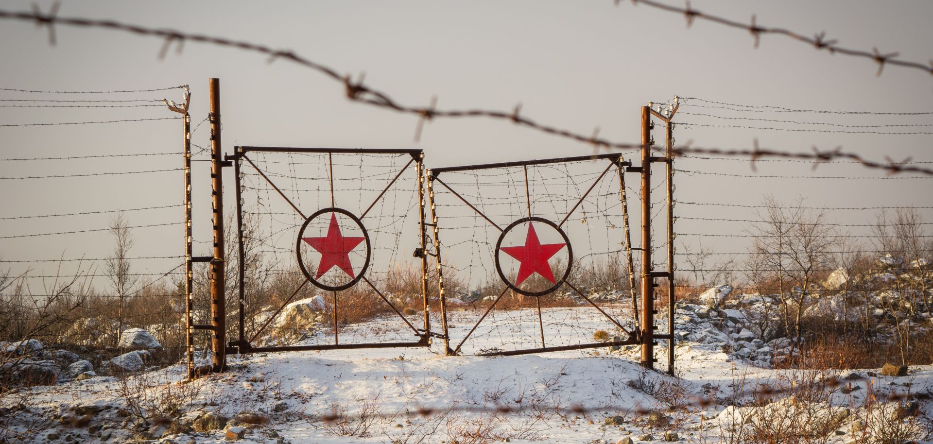 A picture of rusted gates with the star of the former Soviet Union on them. 