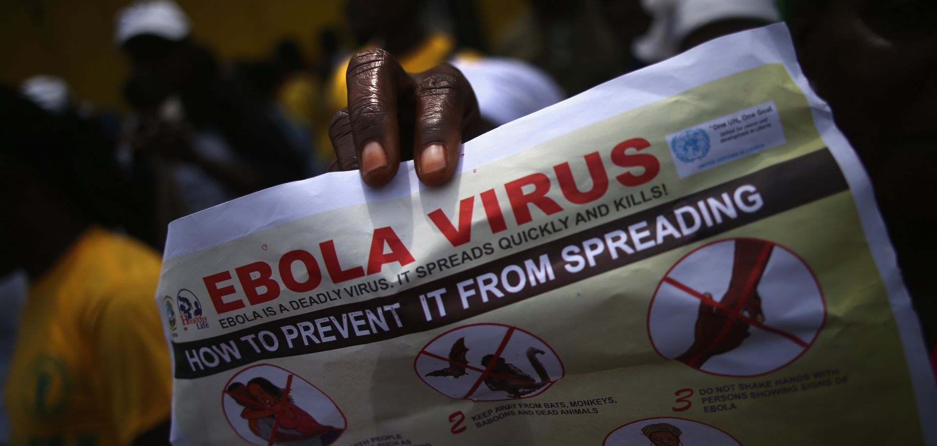 A person holds up a flyer for an event on Ebola awareness.