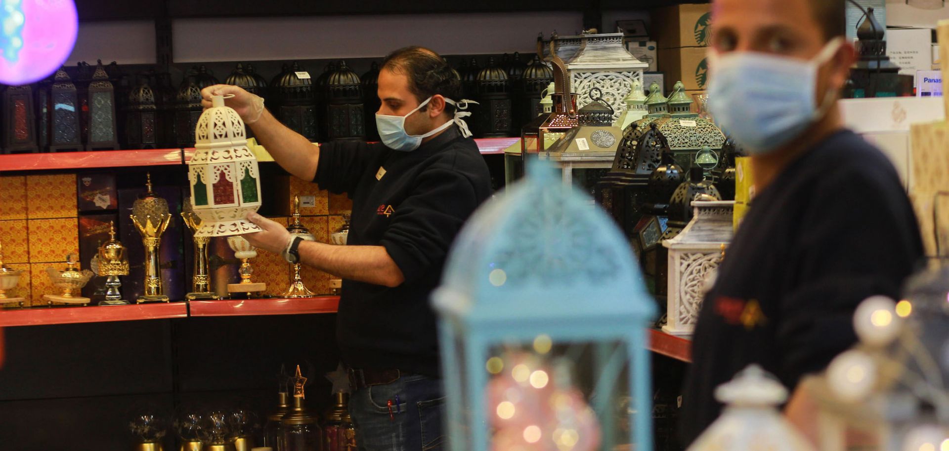 A vendor (L) wearing a face mask holds a traditional Ramadan lantern at a market in Gaza City on April 7, 2020.