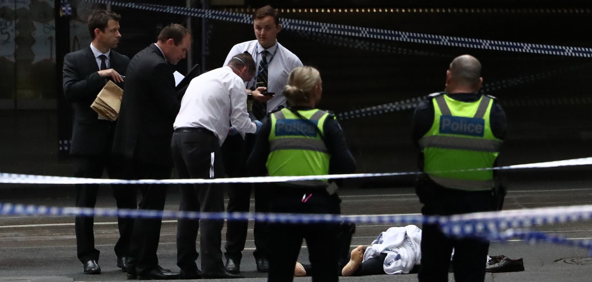 Police examine a body on a street in Melbourne on Nov. 9, 2018. A man was shot by police after setting his car on fire and stabbing three people, killing one. The man was arrested at the scene and taken to hospital in critical condition.