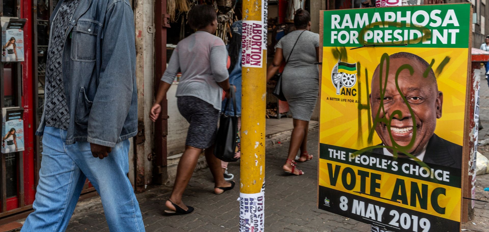 People in Johannesburg walk past an election poster promoting the African National Congress on April 28, 2019.