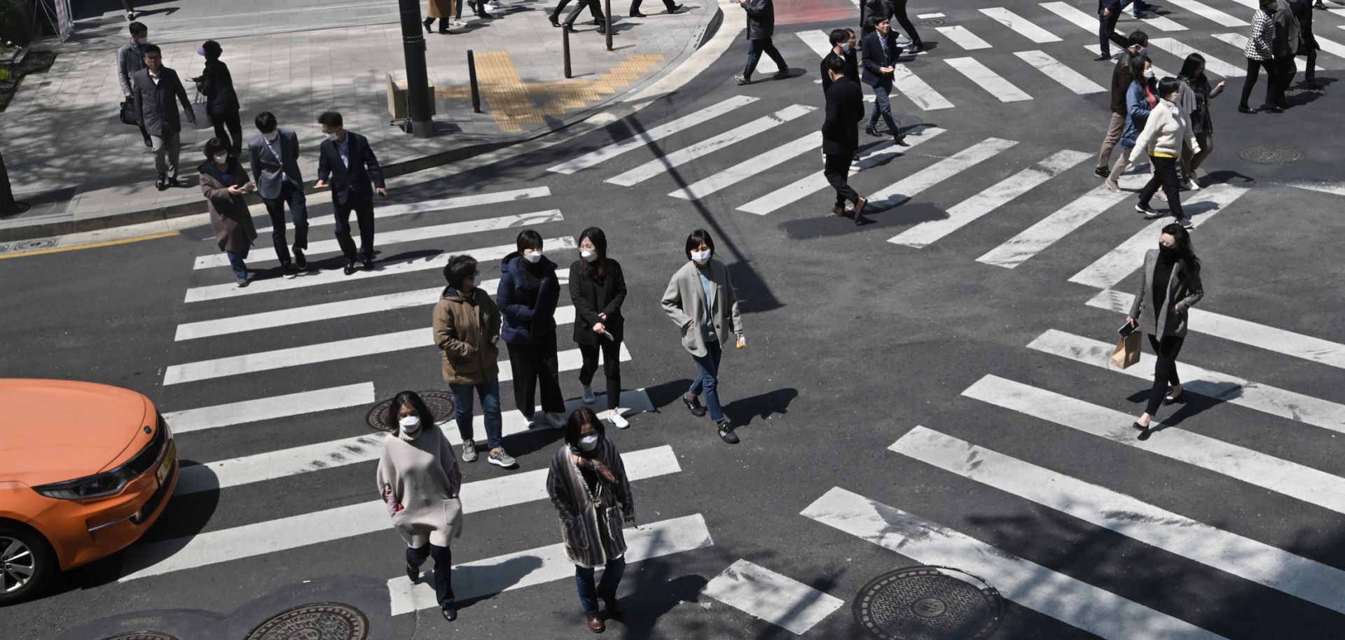 Pedestrians wearing face masks cross an intersection in Seoul, South Korea, on April 23, 2020. In the first quarter of 2020, South Korea's economy saw its worst performance in more than a decade as COVID-19 spread across the country.