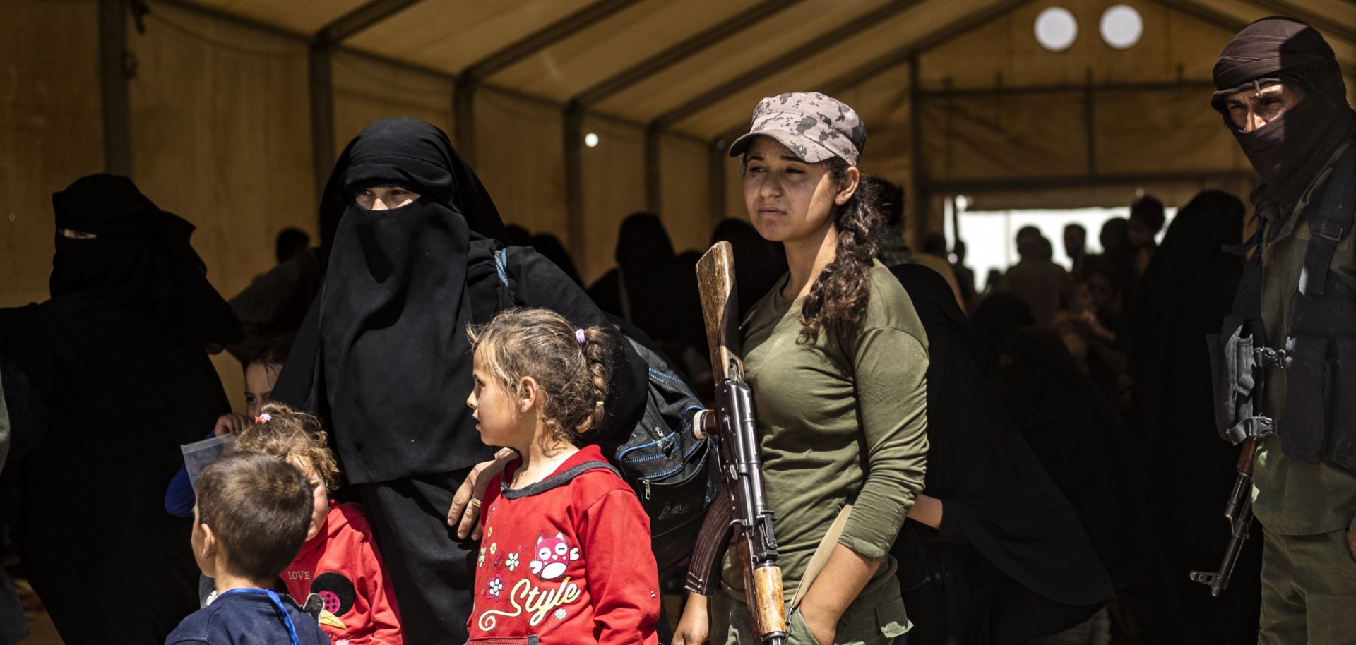 Fighters with the U.S.-backed, Kurdish-led Syrian Democratic Forces guard women and children waiting to leave the al-Hol camp in northeastern Syria on June 3, 2019.