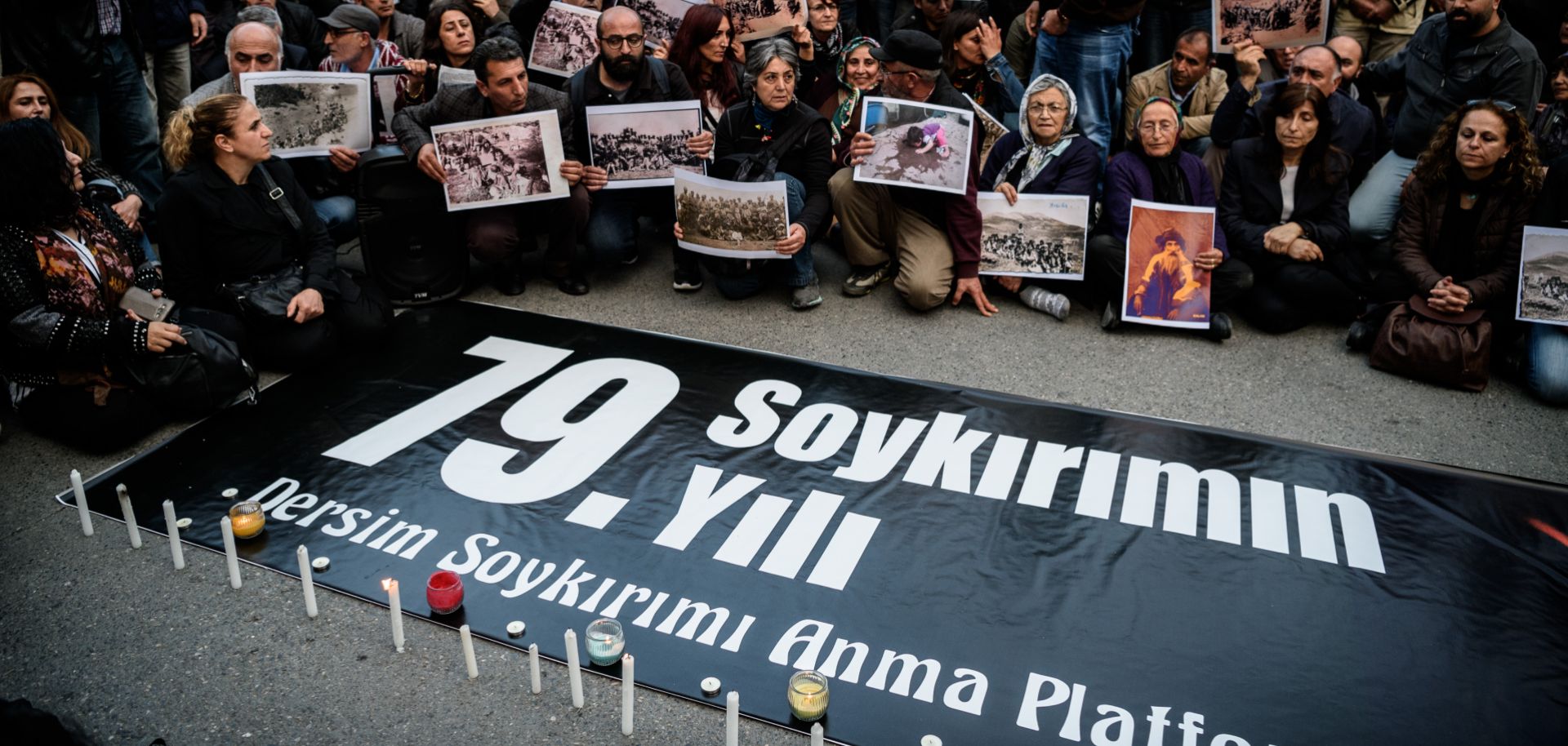 People hold pictures depicting victims of the Dersim operation in the 1930s, behind a placard marking the 79th anniversary of the genocide during a demonstration on May 4, 2016 in Istanbul.