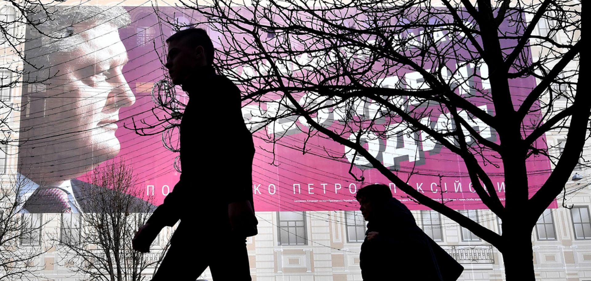 Passersby walk past a giant electoral poster of Ukrainian President Petro Poroshenko displayed on a building in central Kiev on March 22, 2019.