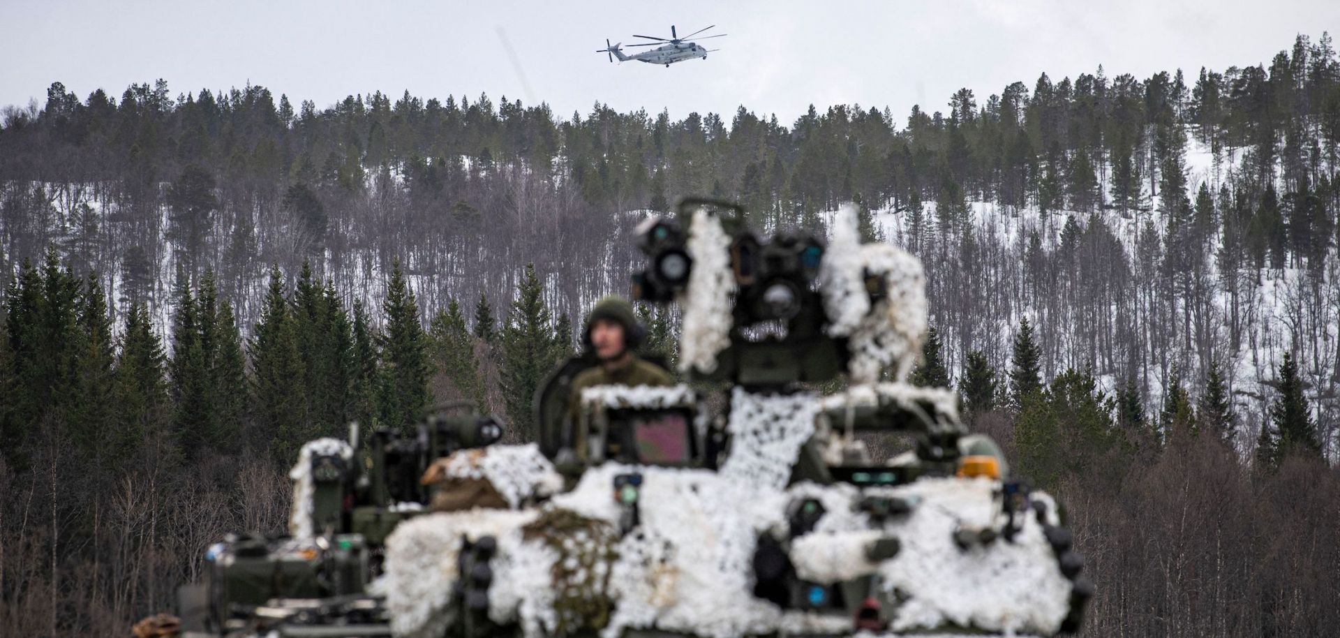 A heavy-lift helicopter operated by the U.S. military flies over a tank in Setermoen, Norway, during a military exercise involving NATO troops and partner countries on March 22, 2022. 