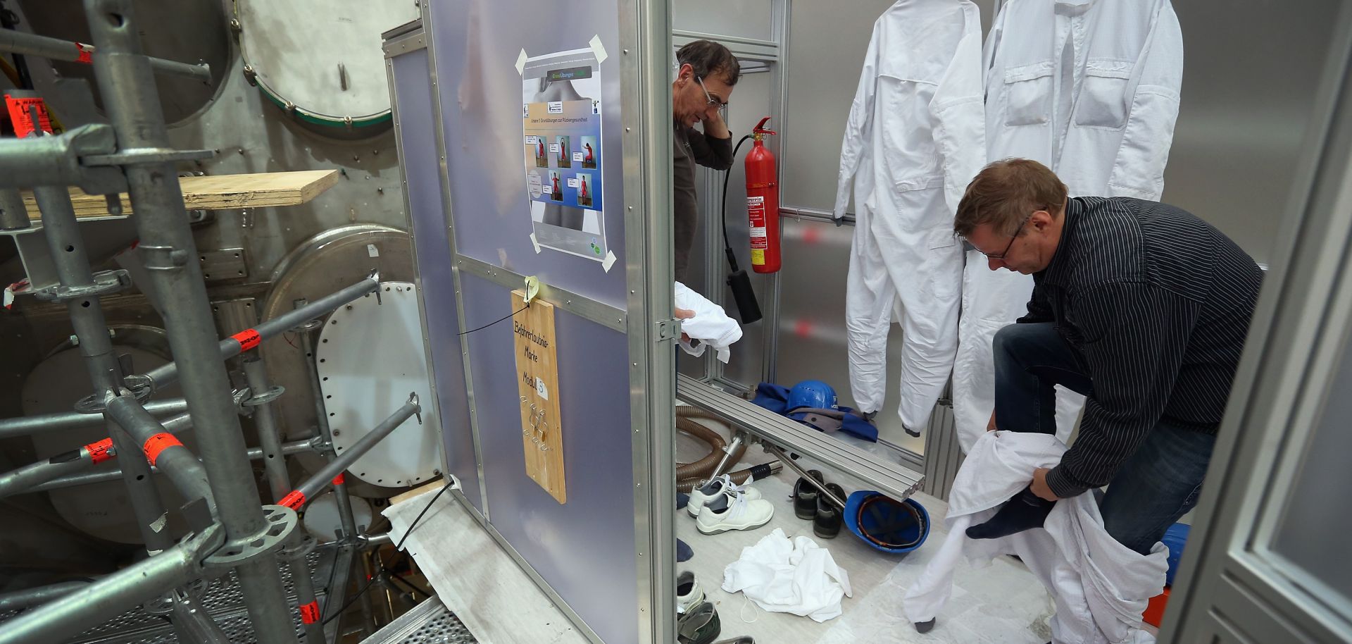 Workers remove special suits after emerging from an interior plasma chamber.