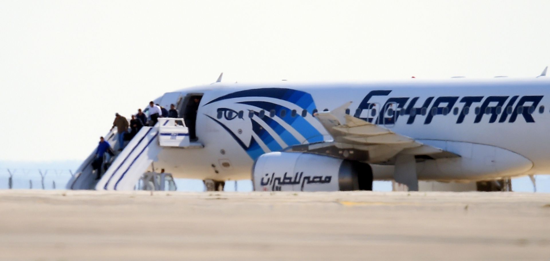 Passengers exit an EgyptAir Airbus A-320 sitting on the tarmac of Larnaca airport after it was hijacked and diverted to Cyprus on March 29, 2016.