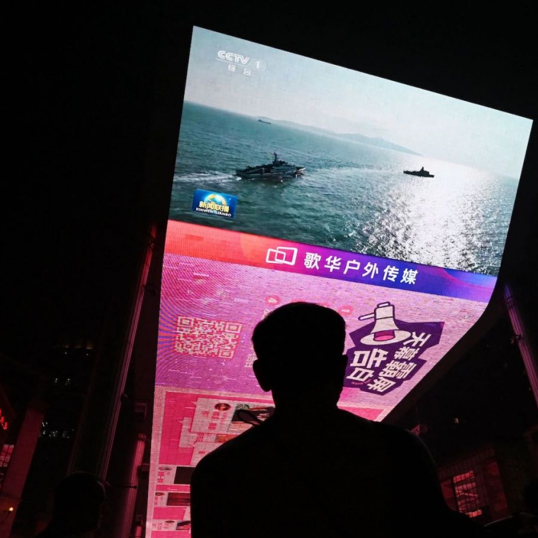 A man watches a news program about Chinese military drills surrounding Taiwan on a giant screen outside a shopping mall in Beijing on Oct. 14, 2024.