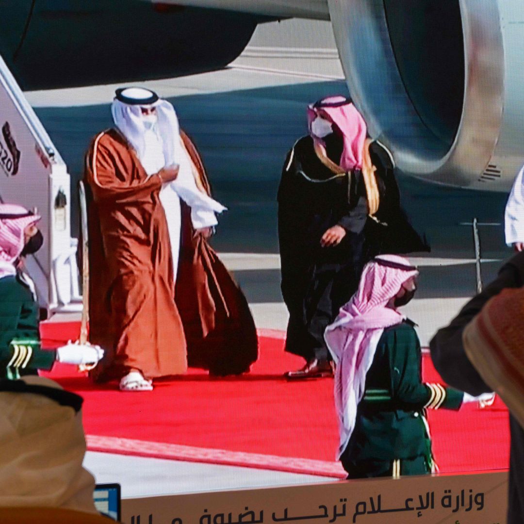 Journalists watch Saudi Crown Prince Mohammed bin Salman (center right) welcome Qatar’s Sheikh Tamim bin Hamad Al Thani (center left) on a screen ahead of the Gulf Cooperation Council (GCC) summit in the Saudi city of al-Ula on Jan. 5, 2021. 