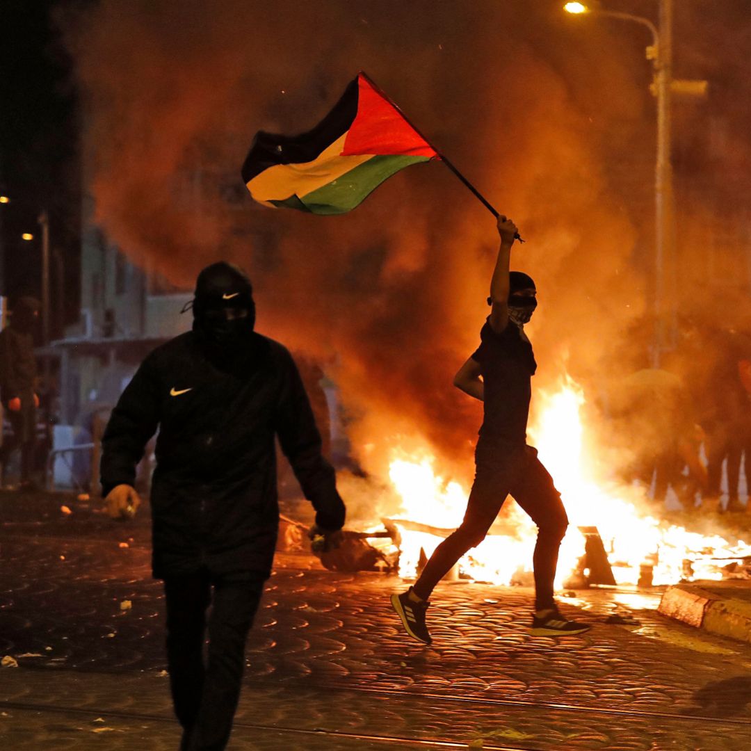 Palestinian protesters hurl stones during clashes with Israeli forces in Israeli-annexed east Jerusalem on May 14, 2021. 