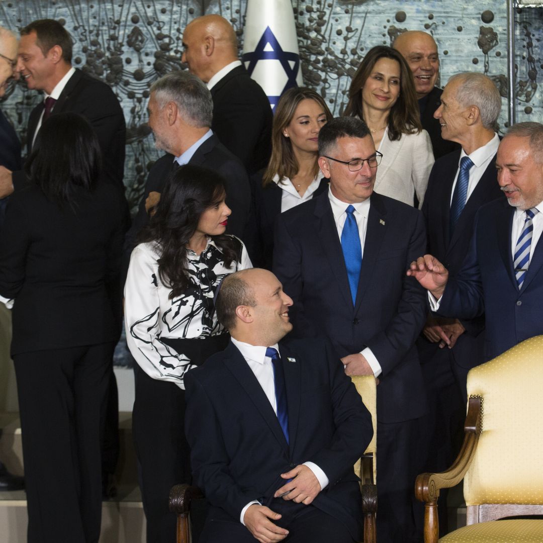 Israeli Prime Minster Naftali Bennett (bottom center) talks with members of his new coalition government before posing for a group photo at the President's Residence in Jerusalem on June 14, 2021. Israeli Prime Minster Naftali Bennett (bottom center) talks with members of his new coalition government before posing for a group photo at the President's Residence in Jerusalem on June 14, 2021.