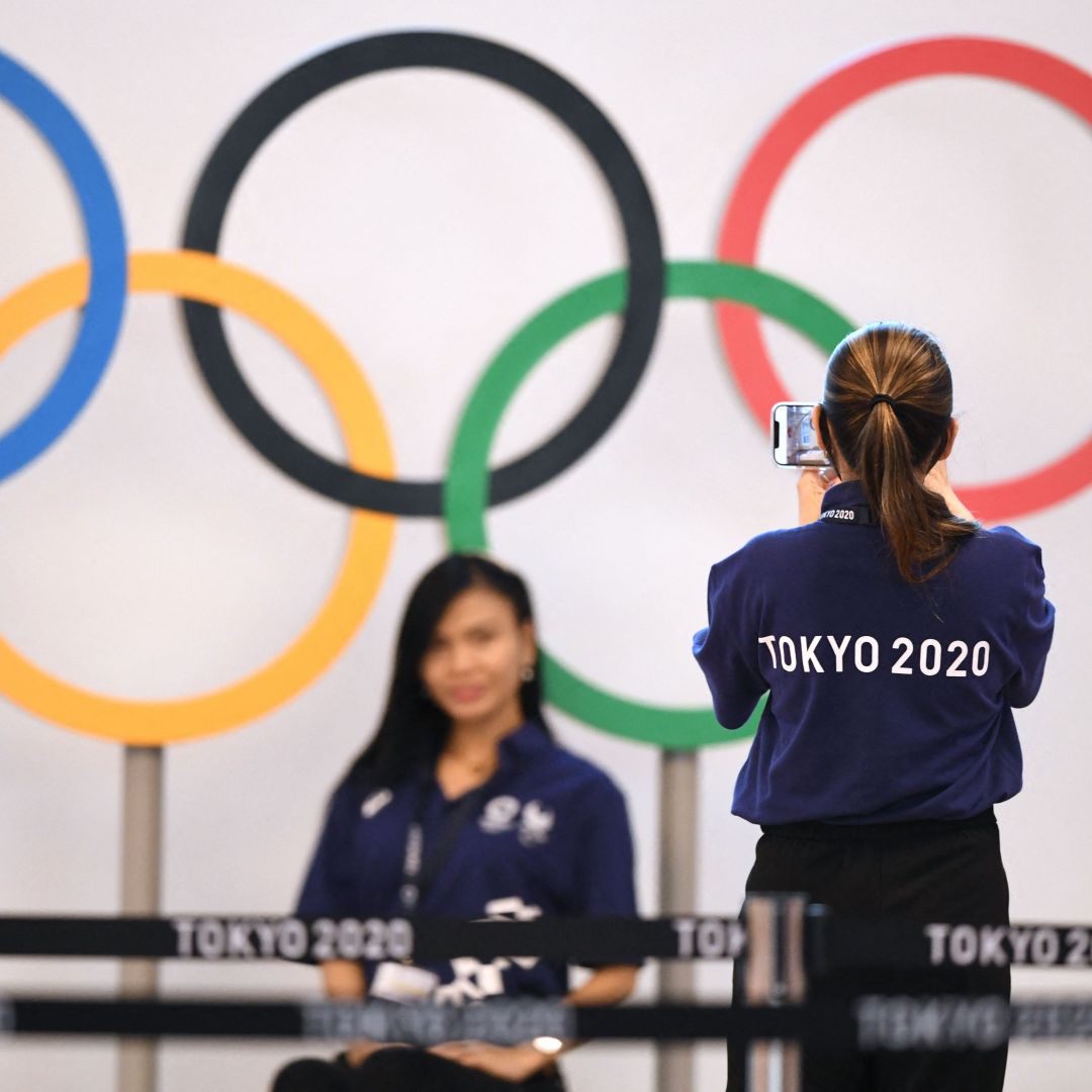 Workers take a picture in front of the Olympic rings at the international airport in Tokyo, Japan, on July 15, 2021.