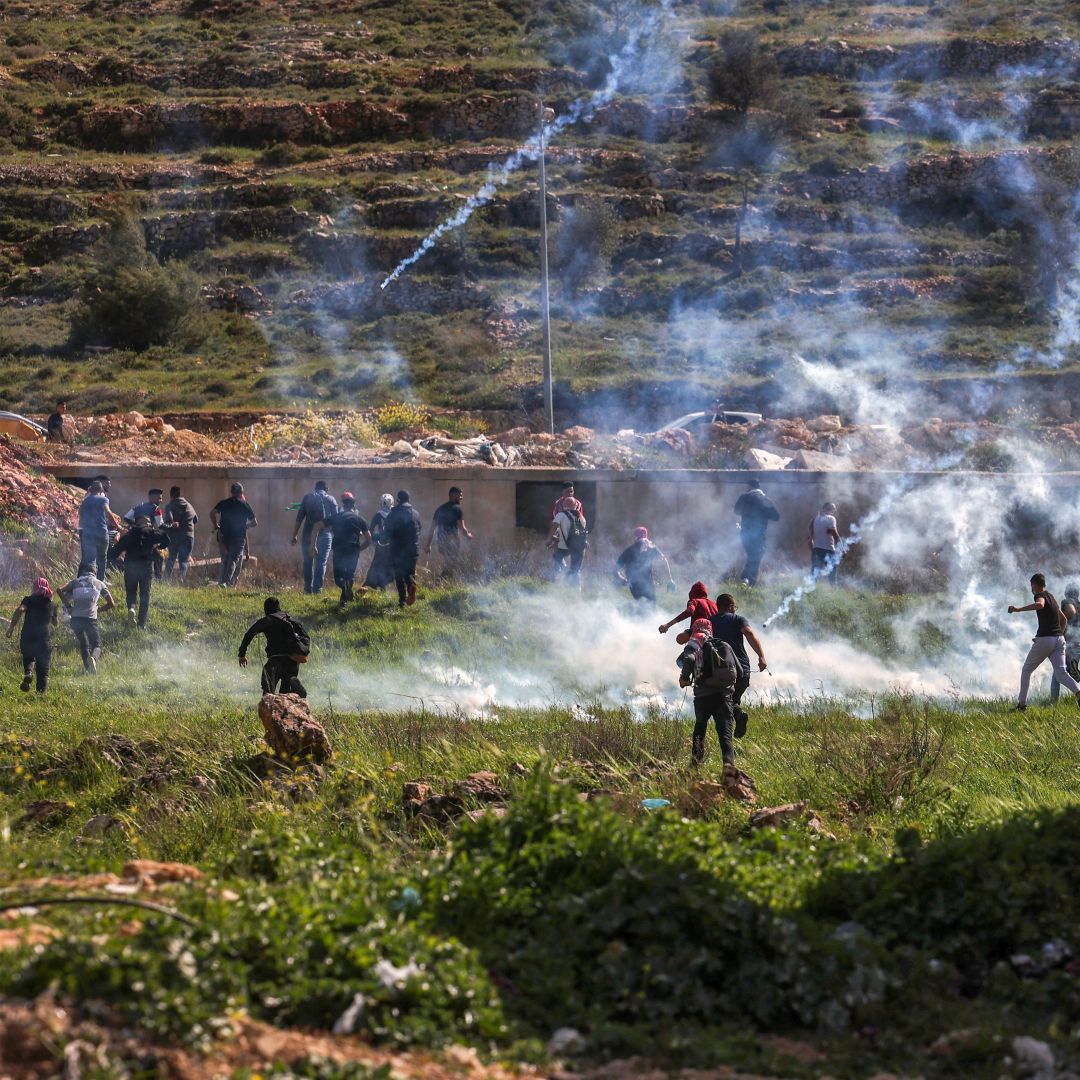 Palestinians run for cover during clashes with Israeli security forces near the Israeli settlement of Beit El in the occupied West Bank on April 11, 2022. Palestinians run for cover during clashes with Israeli security forces near the Israeli settlement of Beit El in the occupied West Bank on April 11, 2022.