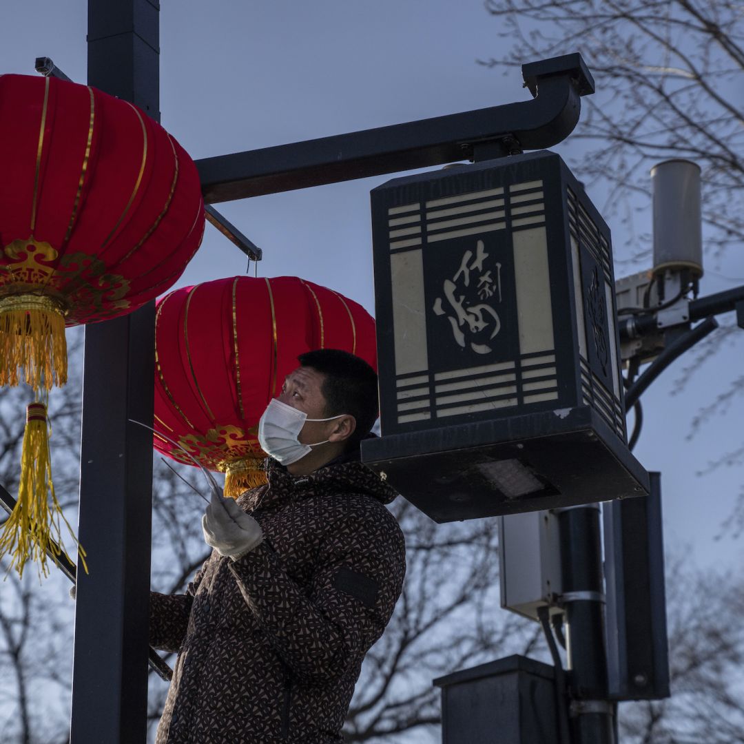 A worker hangs traditional red lanterns for the upcoming Spring Festival on Feb. 3, 2021, in Beijing.