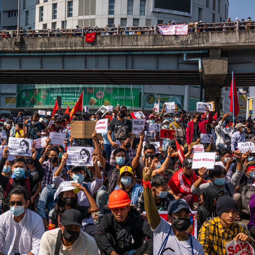 Anti-coup protesters wave red National League For Democracy (NLD) flags and raise three-finger salutes on Feb. 9, 2021, in Yangon, Myanmar. 