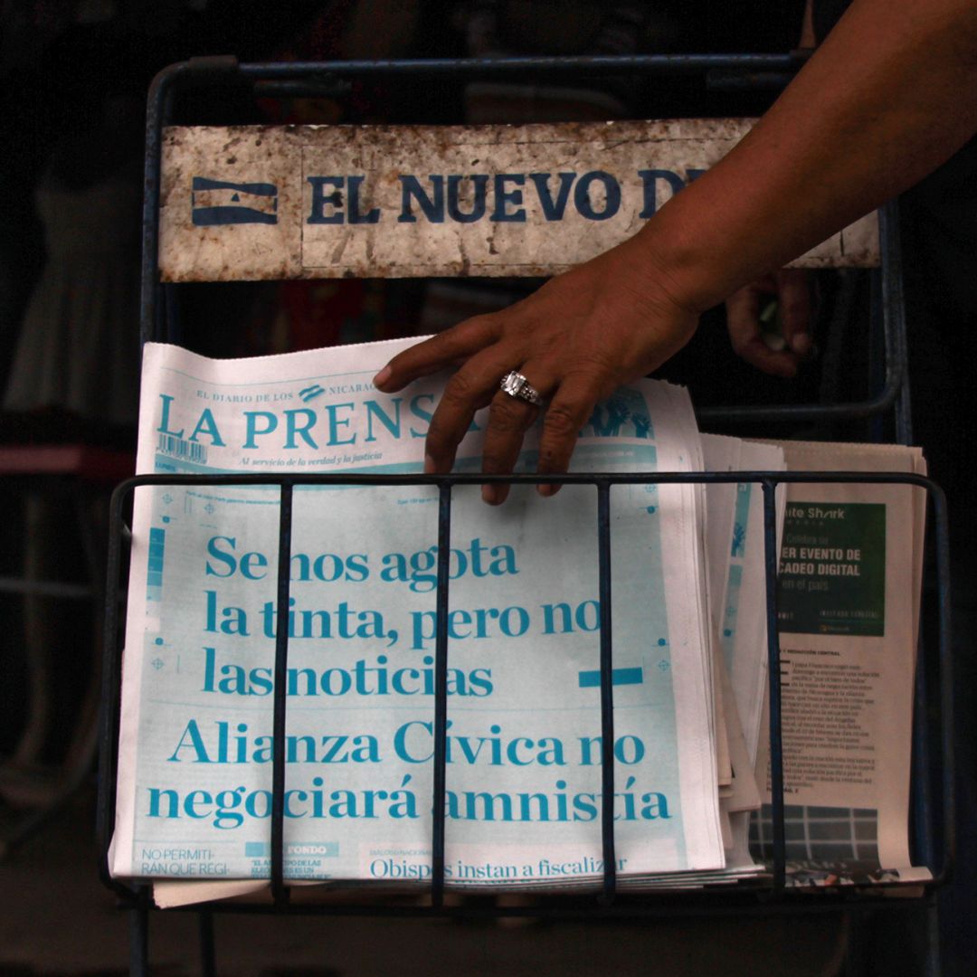 A passerby picks up a copy of Nicaragua's La Prensa in Managua on March 25, 2019. The newspaper printed its cover in cyan, instead of black, with the headline, 'We are running out of ink, but not of news. The Civic Alliance will not negotiate an amnesty.'